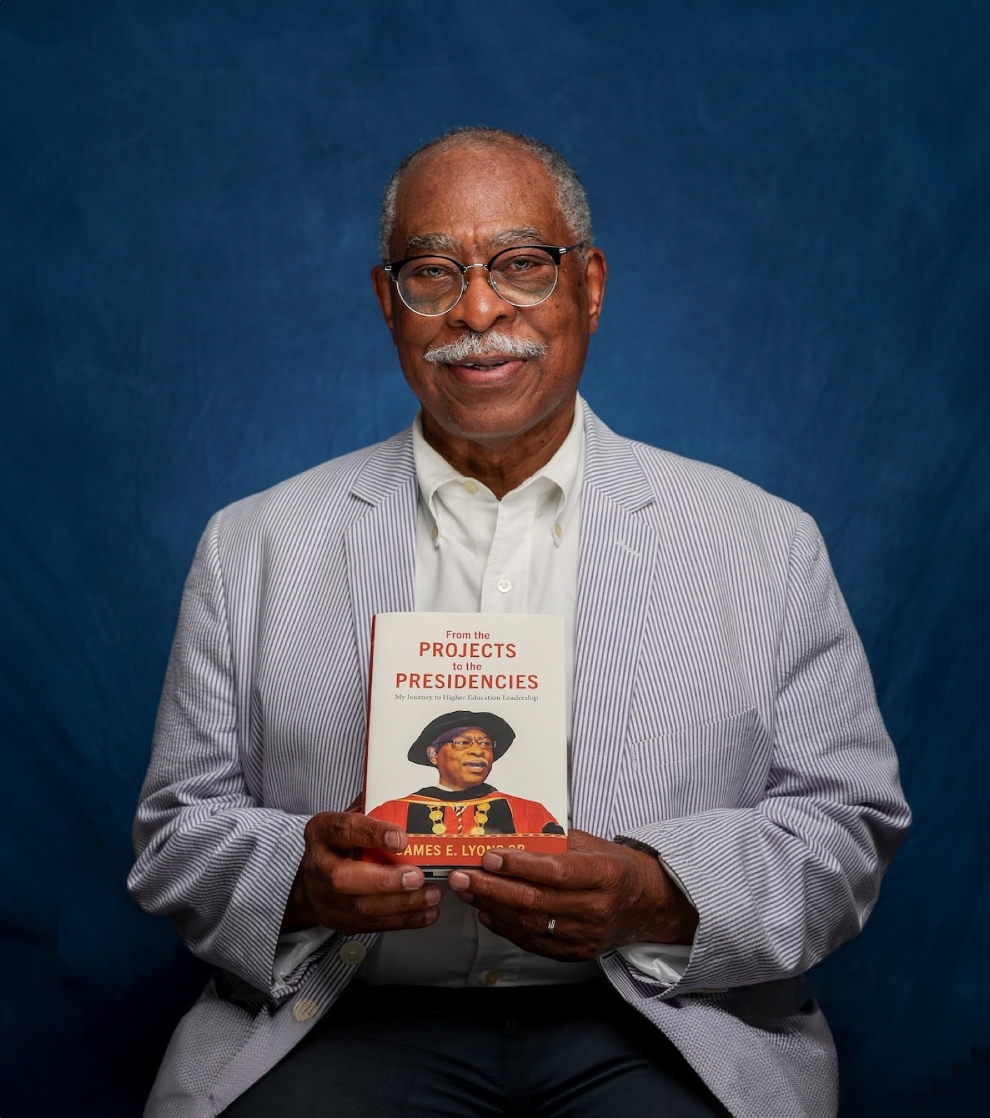 Dr. James E. Lyons, Sr. holding a copy of From the Projects to the Presidencies